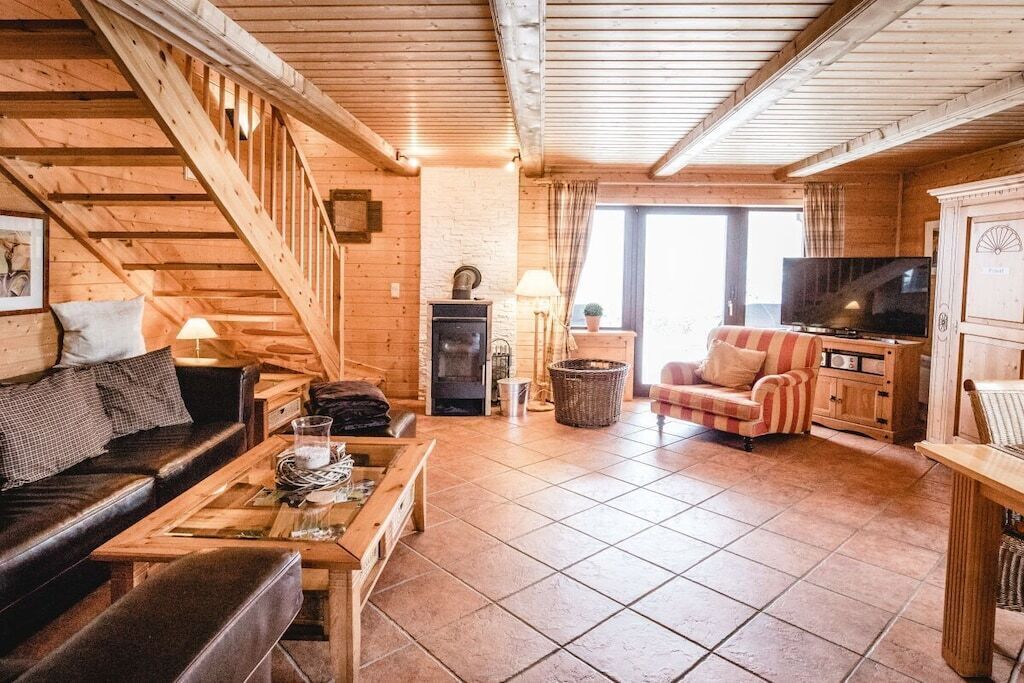A wooden interior with a staircase, a fireplace, a television, and a sofa.