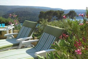 Two striped lounge chairs with cushions, a table with a blue cup, and a view of a mountainous landscape. - Holiday home with 3 bedrooms (Esparron de Verdon)