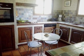 A compact kitchen with a tiled backsplash, a stove, a sink, and a dining area with two chairs. - Holiday home with 3 bedrooms (Esparron de Verdon)