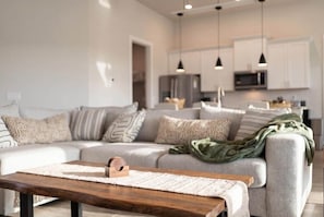 A modern living room with a sectional sofa, a wooden coffee table, and pendant lighting. - Private Accommodation in Cape Coral—Waterfront with a Pool and a Stunning View (Cape Coral)