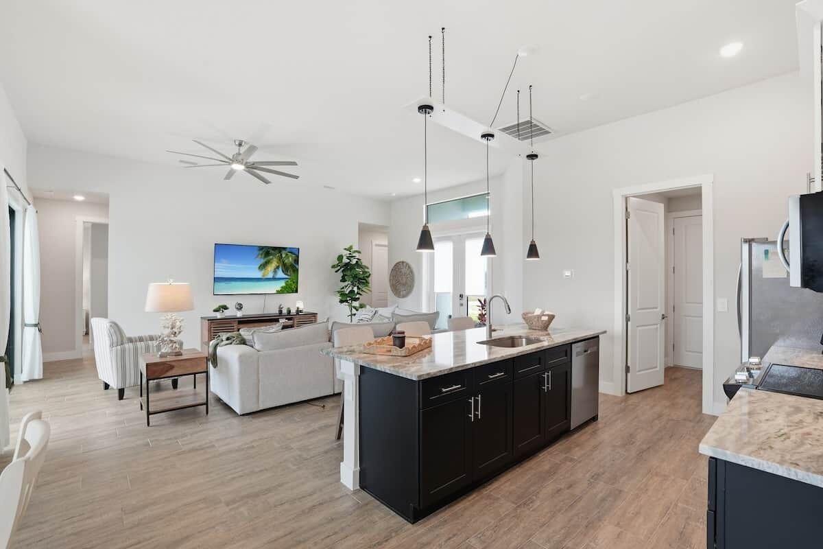A modern kitchen with a central island, black cabinets, and pendant lighting.