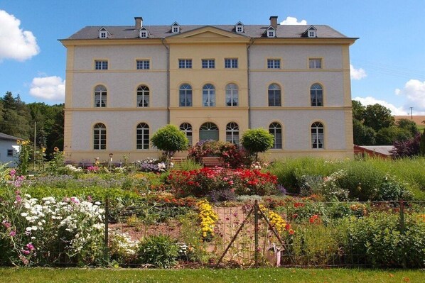 Un grand bâtiment à deux étages, doté d’une façade symétrique, de nombreuses fenêtres et d’une entrée centrale.