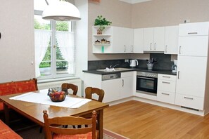 A modern kitchen with white cabinets, a black countertop, and a dining table with chairs.