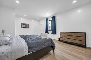 A bedroom with a bed, a dresser, a window with curtains, and a wall with a poster. - Stylish Townhome w/ 4 King Beds, Walk to ASU (Tempe)