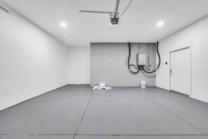 A clean, empty room with a grey floor, white walls, and a door on the right. - Stylish Townhome w/ 4 King Beds, Walk to ASU (Tempe)