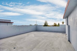 Een dakterras met een heldere lucht, een betonnen vloer en witte muren.