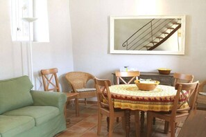 Ein Essbereich mit einem runden Tisch, Stühlen, einem grünen Sofa und einer Treppe.