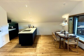 A modern kitchen with a central island, dining table with chairs, and a large window providing a view. - Holiday apartment with 1 bedroom (Wertach)