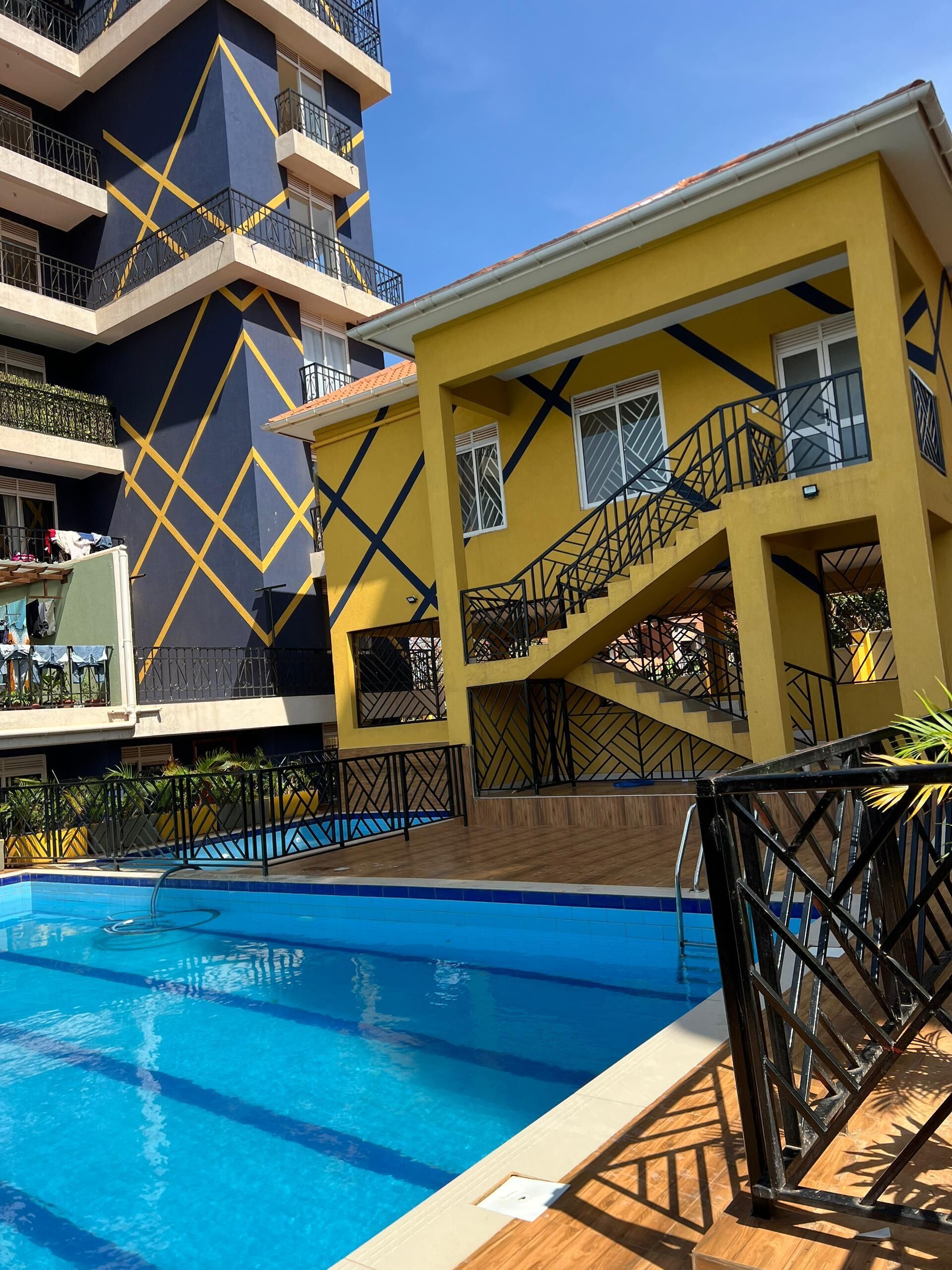 Un immeuble à plusieurs étages doté d’une piscine, de balcons et d’une façade aux lignes géométriques.