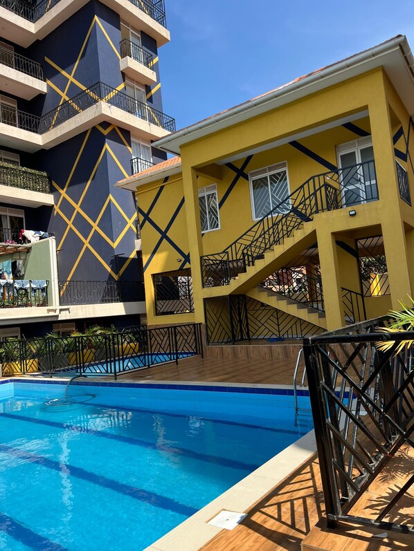 Un immeuble à plusieurs étages doté d’une piscine, de balcons et d’une façade aux lignes géométriques.
