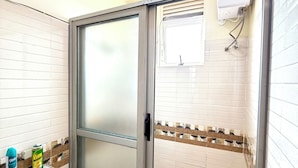 Ein Badezimmer mit Duschabtrennung aus Glas, einem Waschbecken mit einer Flagge als Dekoration und einem Fenster mit einem aufgehängten Handtuch.
