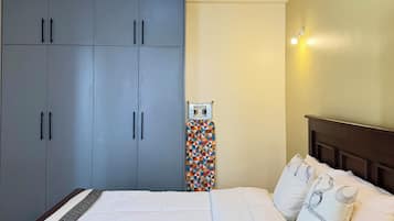 Une chambre à coucher comprenant un lit, une armoire et une planche à repasser fixée au mur.