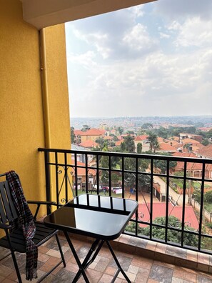 Een balkon met een tafel en stoelen, met uitzicht op een woonwijk met huizen met rode daken.