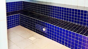 Ein gefliestes Badezimmer mit blau-weißer Farbgestaltung, einer Duschkabine und einem Fliesenboden.