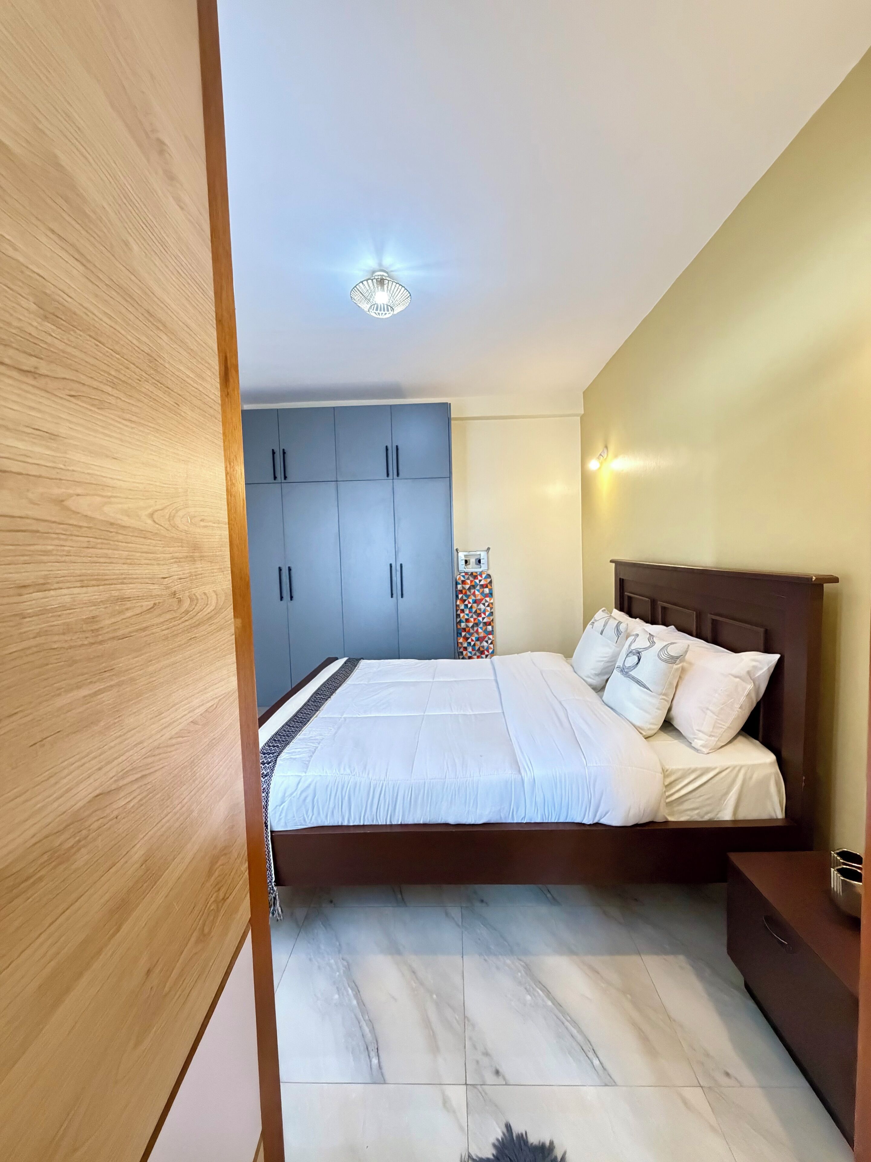 Une chambre à coucher avec un lit, une armoire en bois et une table de chevet.