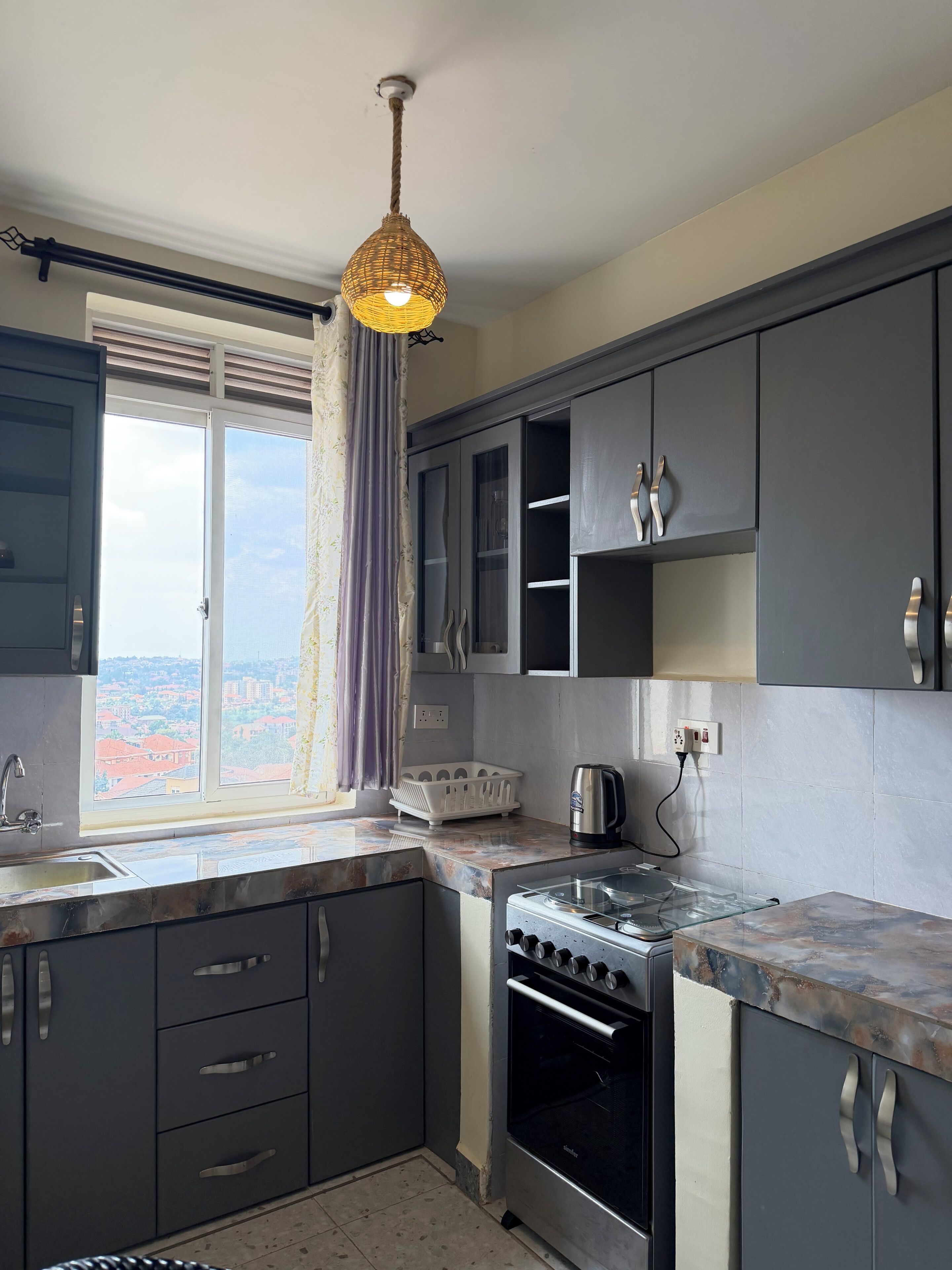 A kitchen with a stove, oven, and a window with a view of buildings.