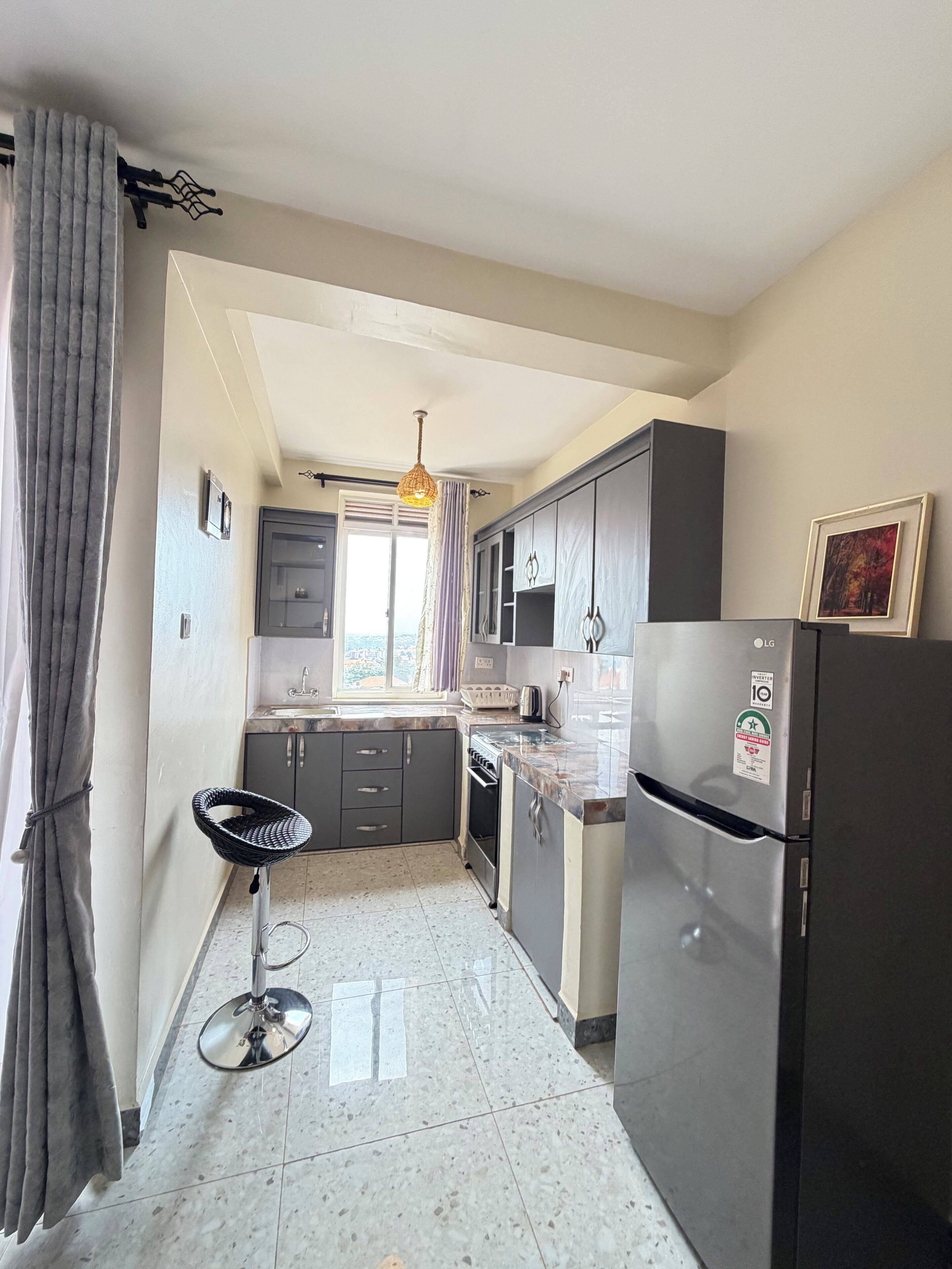 Una cocina con refrigerador, gabinetes, pileta y ventana.
