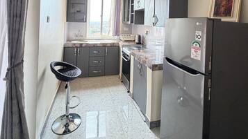 Una cocina con refrigerador, gabinetes, pileta y ventana.