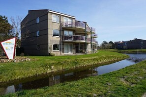Ein mehrstöckiges Gebäude mit Balkonen, einer Rasenfläche und einem Kanal.