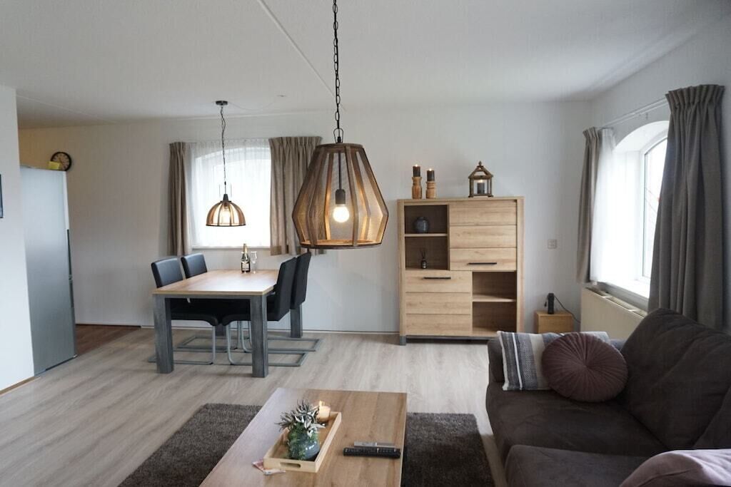 Una sala de estar moderna con comedor, un sofá, una mesa de centro y un aparador de madera.