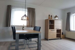 Een eetgedeelte met een houten tafel, stoelen en een hanglamp.