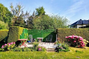 A garden with a green gate, outdoor seating, and flowering plants. - Holiday apartment with 1 bedroom (Kühlungsborn Ost)
