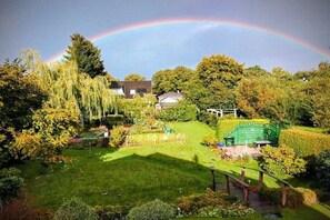 A garden with a rainbow, a wooden fence, and a green structure. - Holiday apartment with 1 bedroom (Kühlungsborn Ost)