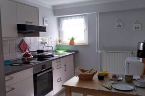 Eine kleine Küche mit Herd, Backofen und einem Fenster mit Vorhängen.