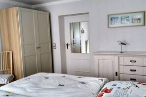 A bedroom with a bed, a wardrobe, a dresser, a mirror, and a framed picture on the wall. - Holiday apartment with 1 bedroom (Kühlungsborn Ost)