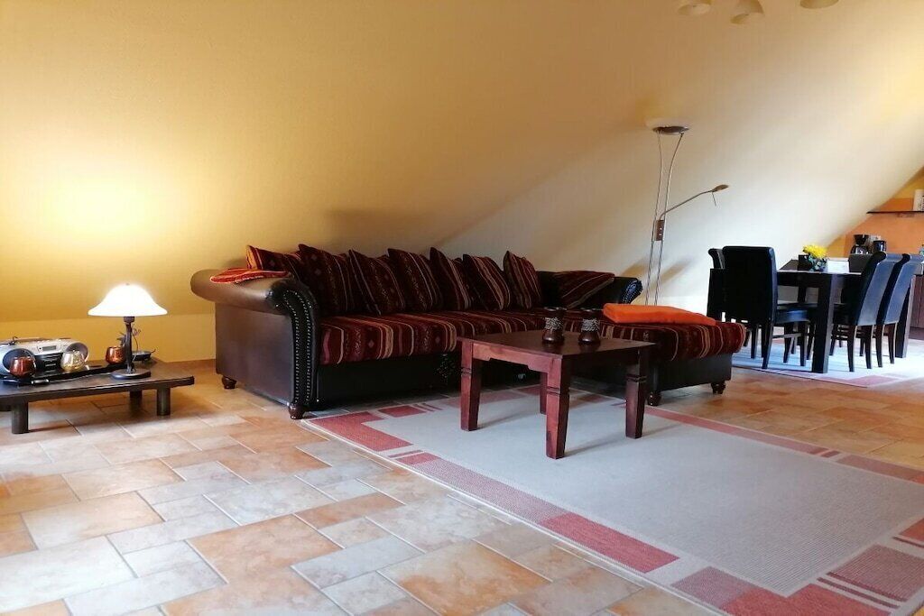 Ein Wohnzimmer mit einer Couch, einem Couchtisch, einer Lampe und einem Essbereich mit Stühlen und einem Tisch.