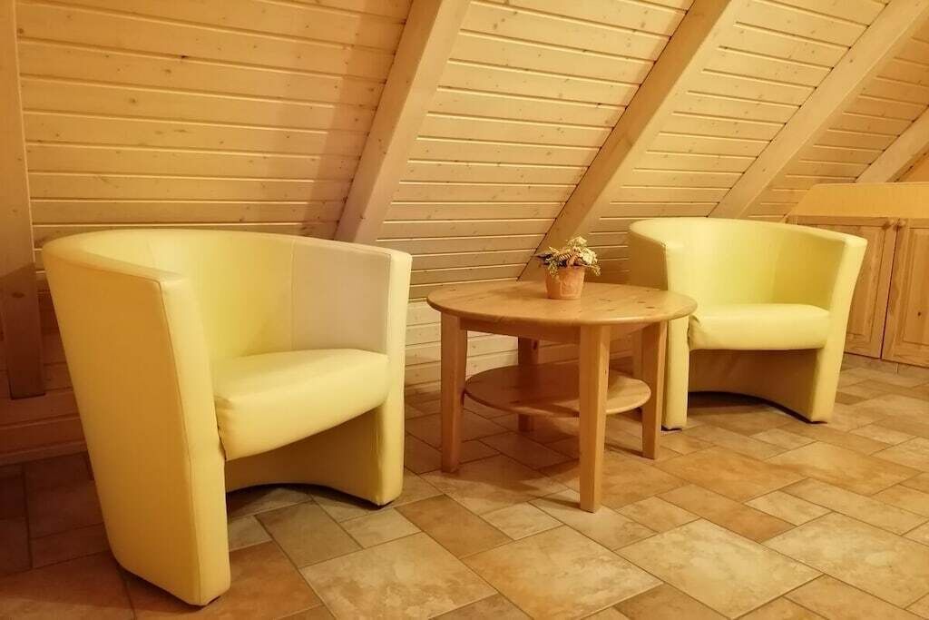 Une pièce avec deux fauteuils jaunes, une petite table en bois et une plante en pot.