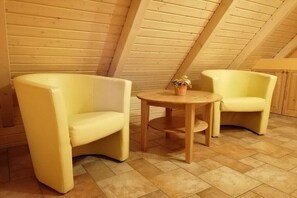 A room with two yellow armchairs, a small wooden table, and a potted plant. - Holiday apartment Sterntaucher 04 (Ostseebad Ahrenshoop)