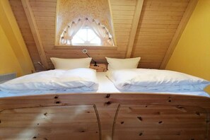 A bedroom with a wooden ceiling and a window with a curtain. There are two beds with white bedding. - Holiday apartment Sterntaucher 04 (Ostseebad Ahrenshoop)