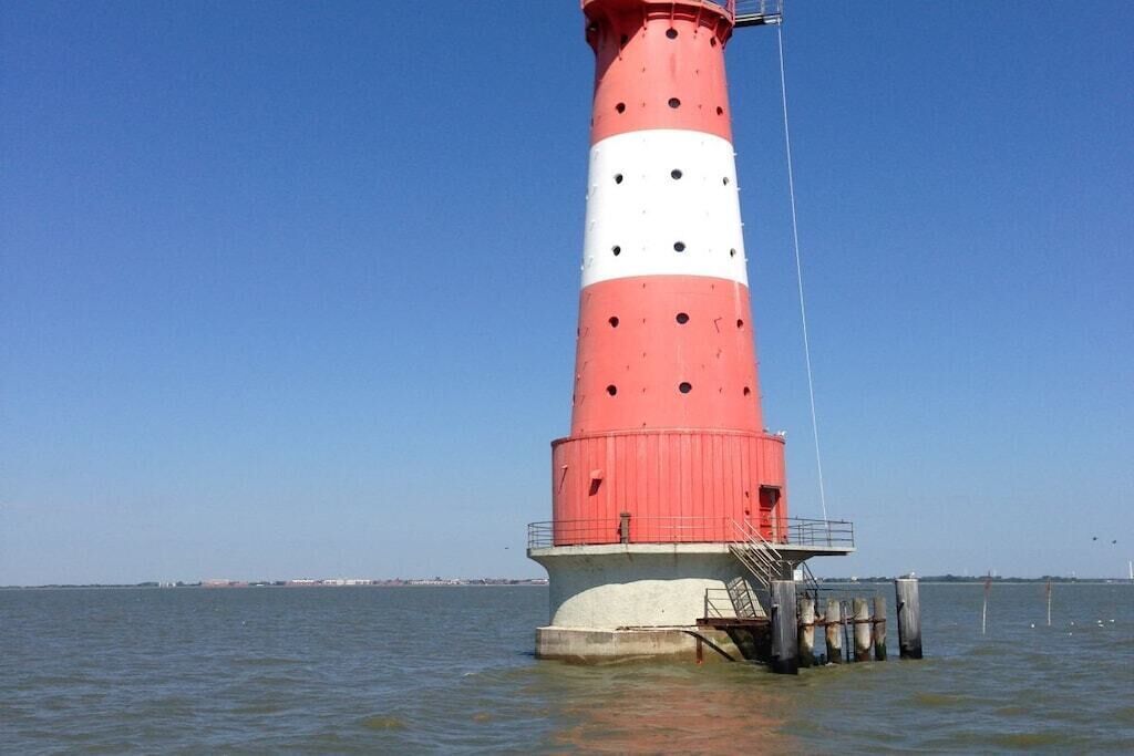 Un faro con una decoración roja y blanca, ubicado junto al agua.