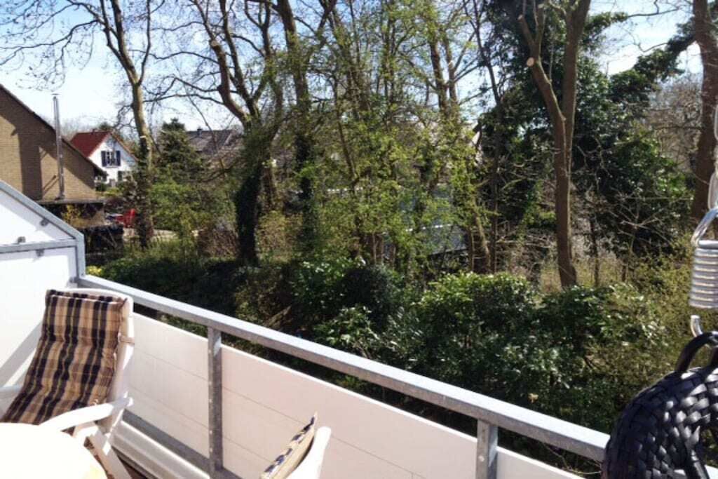 A balcony with a white railing, a wicker chair, and a cushion.