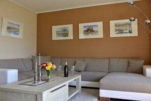 A living room with a grey sofa, a coffee table, and a painting on the wall. - Holiday home in Born on the Darß peninsula with Wi-Fi (Born auf dem Darß)
