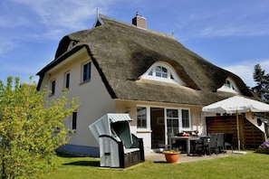 A house with a thatched roof, a patio with outdoor furniture, and a garden. - Holiday home in Born on the Darß peninsula with Wi-Fi (Born auf dem Darß)
