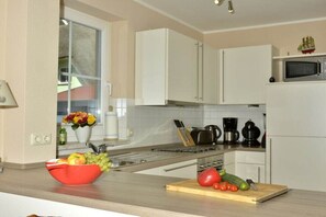 A kitchen with white cabinets, a microwave, a coffee maker, and a fruit bowl on the counter. - Holiday home in Born on the Darß peninsula with Wi-Fi (Born auf dem Darß)