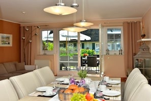 A dining area with a table set for breakfast, including plates, cups, and a fruit basket. - Holiday home in Born on the Darß peninsula with Wi-Fi (Born auf dem Darß)