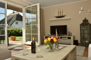 A dining area with a table set for two, a television, and a decorative ship model on the wall. - Holiday home in Born on the Darß peninsula with Wi-Fi (Born auf dem Darß)