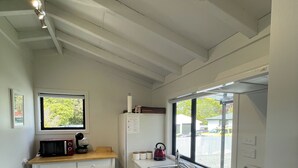 A compact kitchen with a built-in oven, a microwave, and a sink. - Romantic 1-bedroom guesthouse with all the extras! (Te Anau)