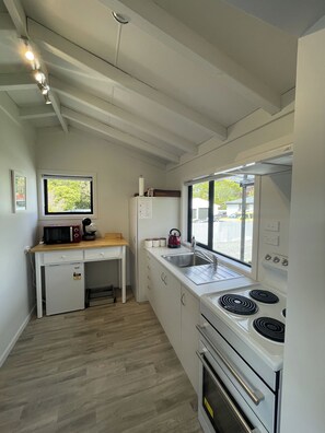Una cocina compacta con horno integrado, microondas y lavabo.