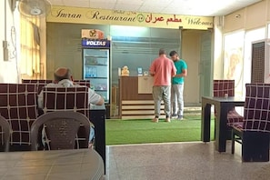 A restaurant interior with a counter, seating area, and a VOLTAS refrigerator. - Hotel Starr Residancy (gurugram)