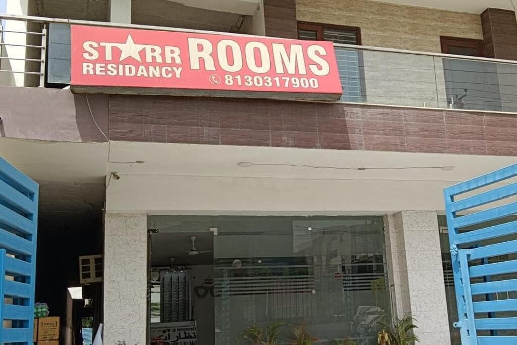 A storefront with a sign for 'Star Rooms Residency' and a contact number.