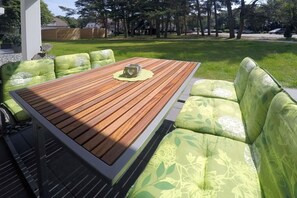 An outdoor seating area with a wooden table and green cushioned benches. - Holiday apartment with 2 bedrooms (Dierhagen)