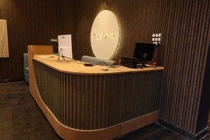 A reception desk with a computer, a telephone, and a sign that reads 'RECEPTION'. - Aachman Hotal Restaurant (Bulandshahr)