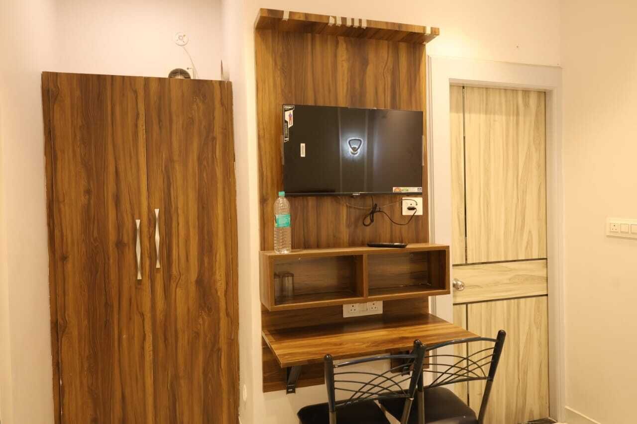 Ein Zimmer mit einem Holzkleiderschrank, einem Wandfernseher und einem kleinen Holztisch mit Stühlen.