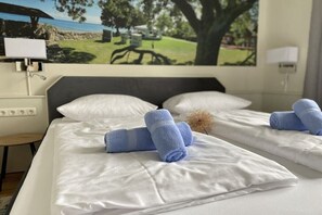 A hotel room with two beds, white linens, and blue towels. - Beach Villa Miramare / Apt. Sea Urchin (Klütz)