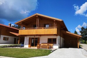 Un edifici de fusta de dos pisos, amb un balcó, un porxo cobert i un camí d'accés pavimentat.