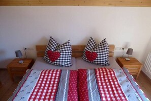A double bed with checkered bedding, two bedside tables with lamps, and heart-shaped pillows. - Holiday home with 3 bedrooms (Lechbruck am See)
